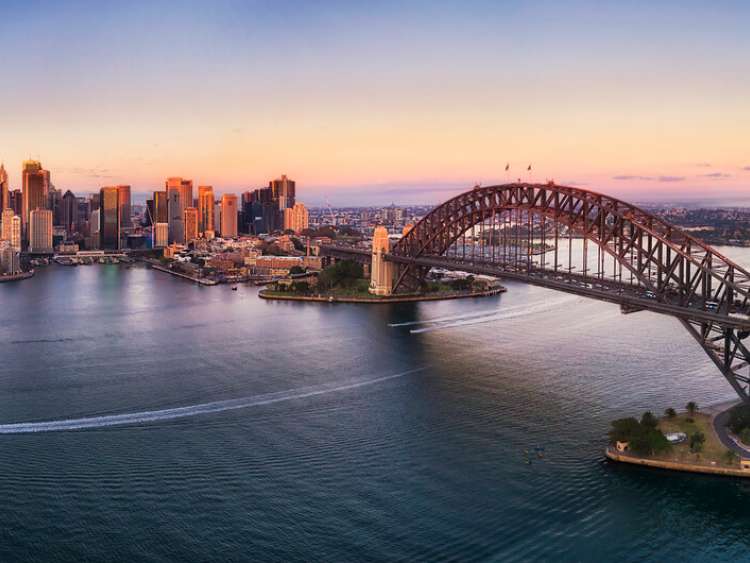 Colourful sky over Sydney city CBD high-rise towers at sunrise around Sydney harbour and the Sydney Harbour bridge in elevated aerial panorama.