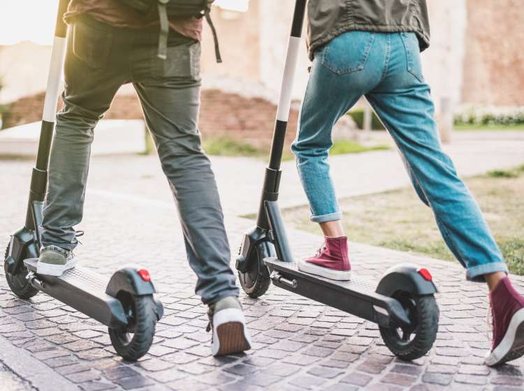 Close up of people couple using electric scooter in city park - Millenial students riding new modern ecological mean of transport - Green eco energy concept with zero emission - Warm sunshine filter