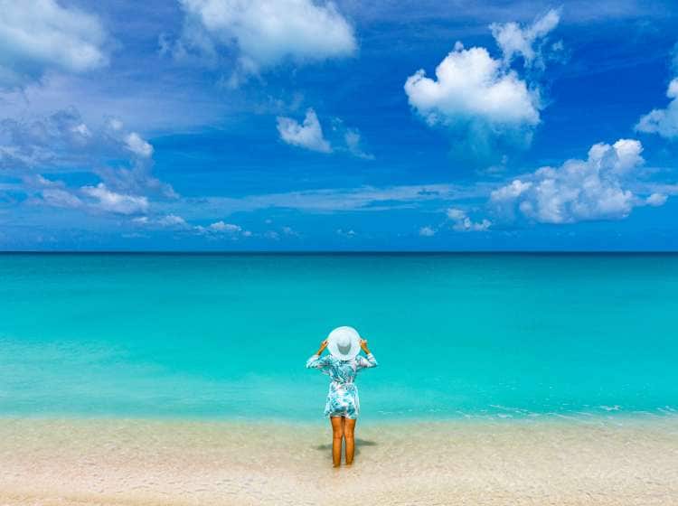 High angle view of woman holding the sun hat sunbathing in the turquoise water of Caribbean Sea, Antigua & Barbuda, West Indies