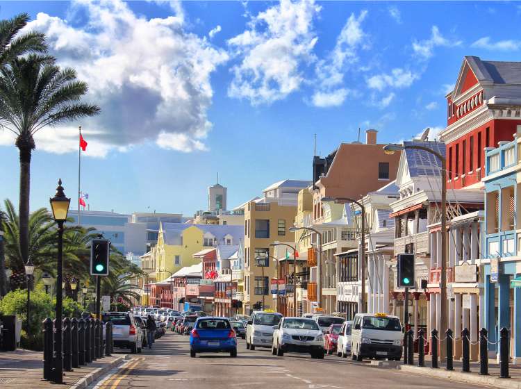 Front Street in Hamilton, the capital of Bermuda. Brightly coloured houses, restaurants and shops and busy traffic.