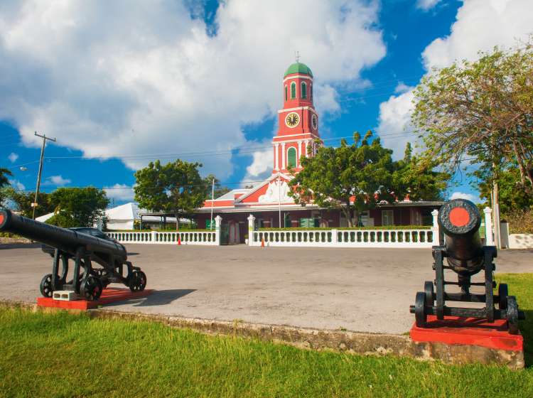 Famous red clock tower on the main guardhouse at the Garrison Savannah with old cannons in front of it. UNESCO garrison historic area Bridgetown, Barbados