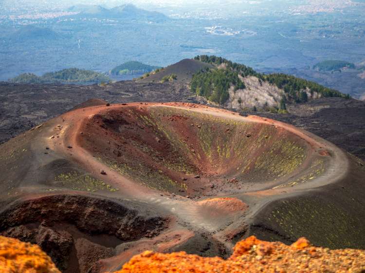 View of the huge and colorful Silvestri crater on Mount Etna, Sicily, Italy, with the city of Catania in the background