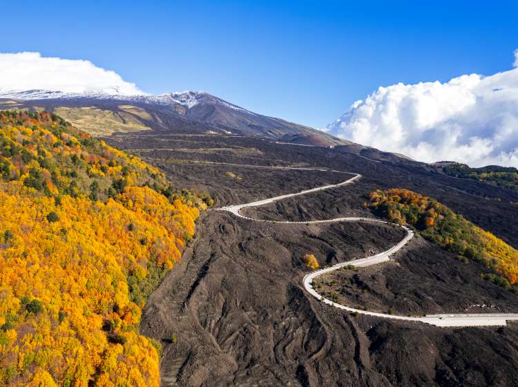 Aerial view of winding road on black lava terrain heading to volcano Etna (UNESCO world heritage site), Nicolosi, Catania, Sicily, Italy