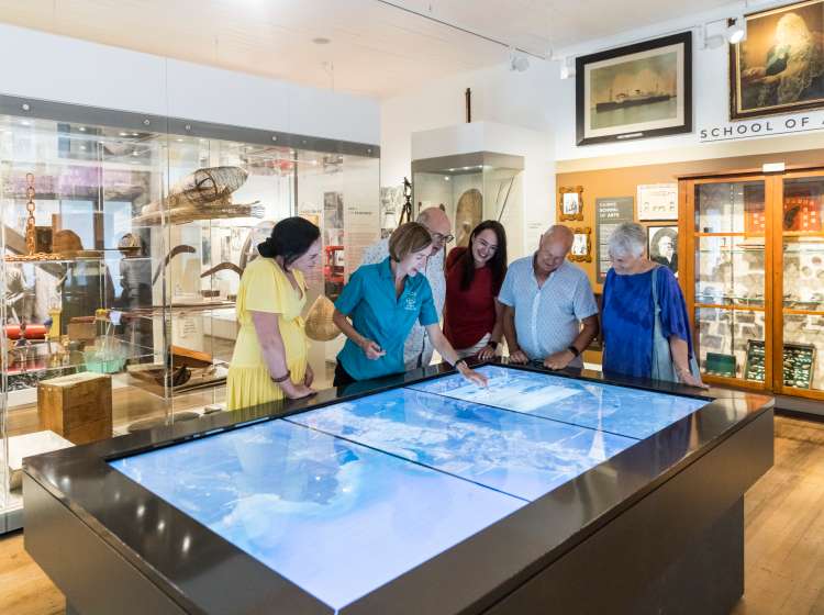 The Cairns Museum guide showing guests an interactive display highlighting the locations, history, culture and people of the Cairns region