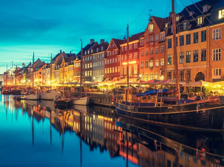 Copenhagen, Denmark - May 23 2022: Beautiful view with colorful facade of traditional houses and old wooden ships along the Nyhavn Canal or New Harbour, canal and entertainment district, night view