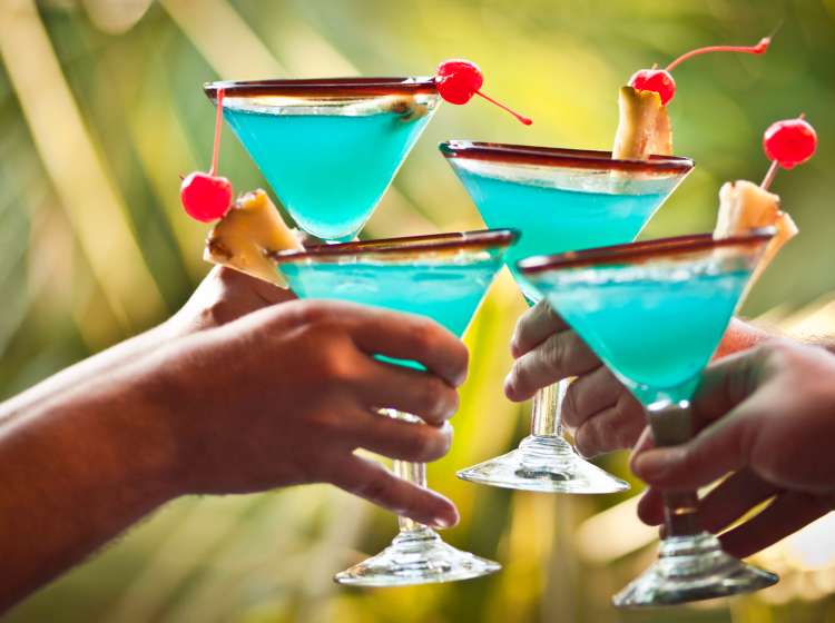 Four friends cheering with Blue Hawaiian drinks.