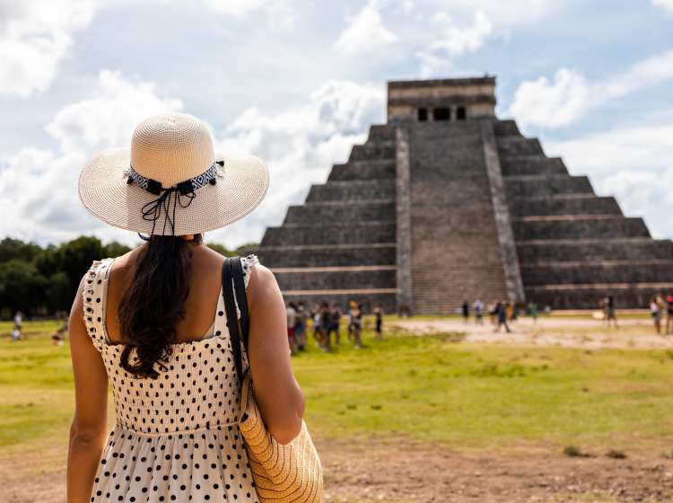 Latin woman visiting Chichen Itza pyramid in Mexico. She is enjoying beautiful view