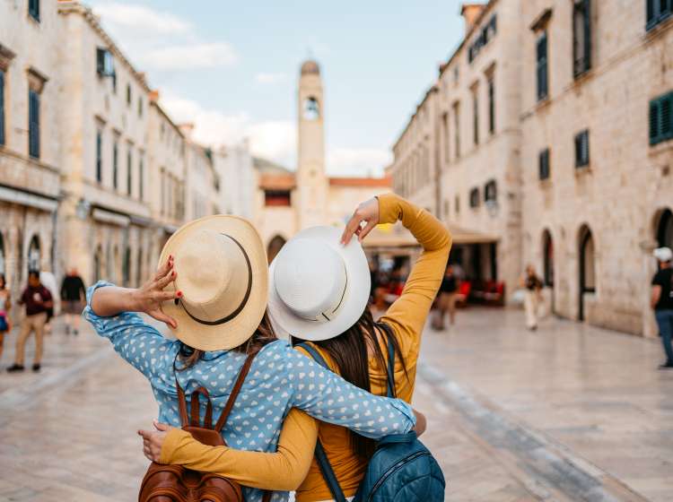 Two young female tourists embracing on the street in Dubrovnik in Croatia.
