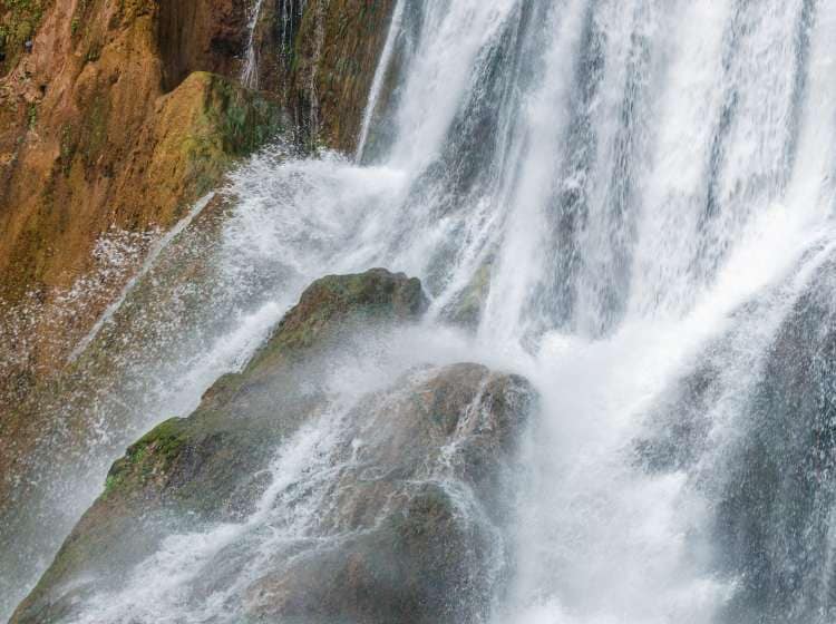 Waterfall close up water drops on rock. Close-up side view