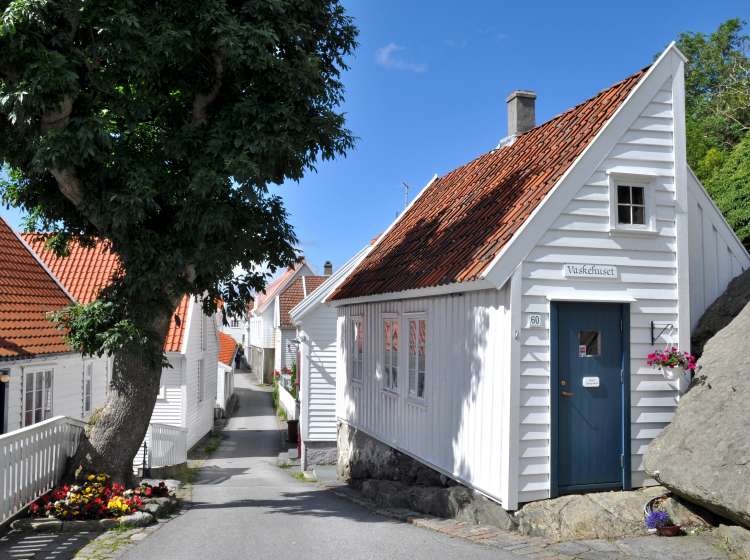 Skudeneshavn, Norway - August 10, 2011: Narrow idyllic alley with white wooden houses in Skudeneshavn on the island Karm0y in southern Norway