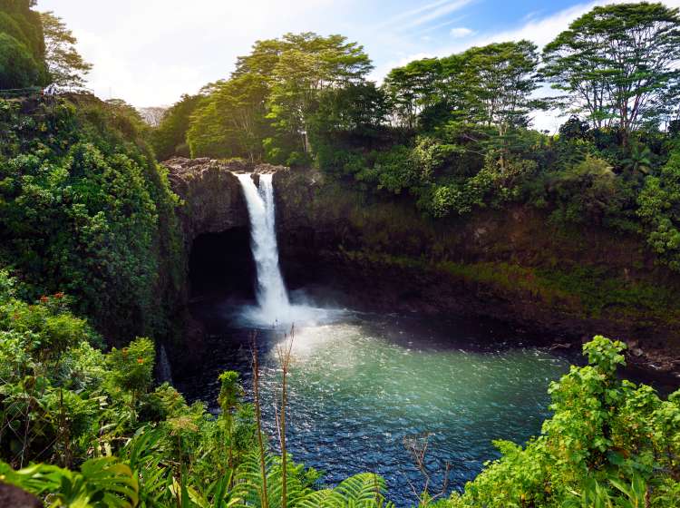 Majesitc Rainbow Falls waterfall in Hilo, Wailuku River State Park, Hawaii. The falls flows over a natural lava cave, the mythological home to Hina, an ancient Hawaiian goddess.
