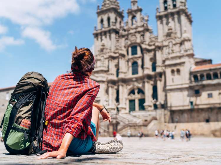 Woman backpacker piligrim siting on the Obradeiro square (plaza) in Santiago de Compostela