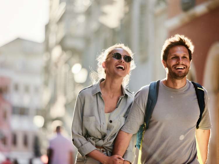 Happy couple holding hands while walking on the city street.