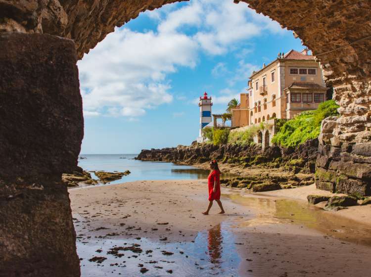 Woman at Santa Marta beach with views of the lighthouse in the back in Cascais, Lisbon, Portugal