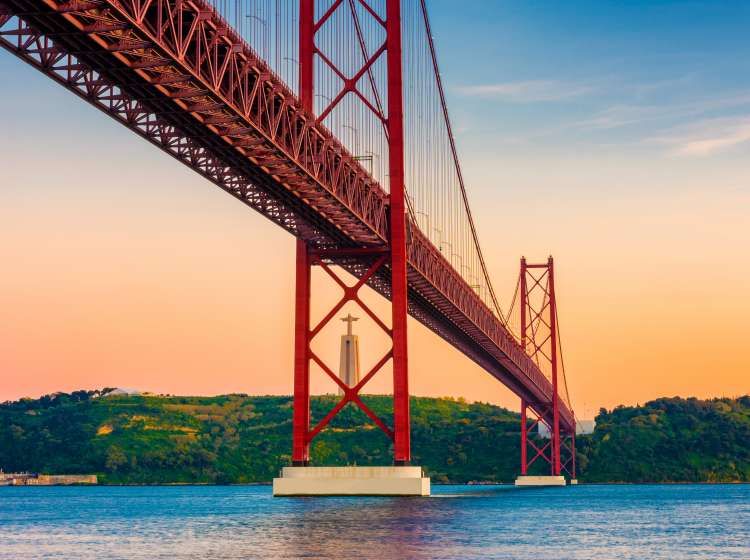 25th of April Bridge, Tagus River and Christ the King statue in Lisbon Portugal around sunset.