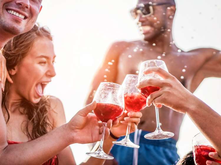 Happy friends drinking sangria wine at exclusive boat party - Young people having fun in summer vacation - Focus on left man hand glass - Travel, friendship, holidays and youth lifestyle concept