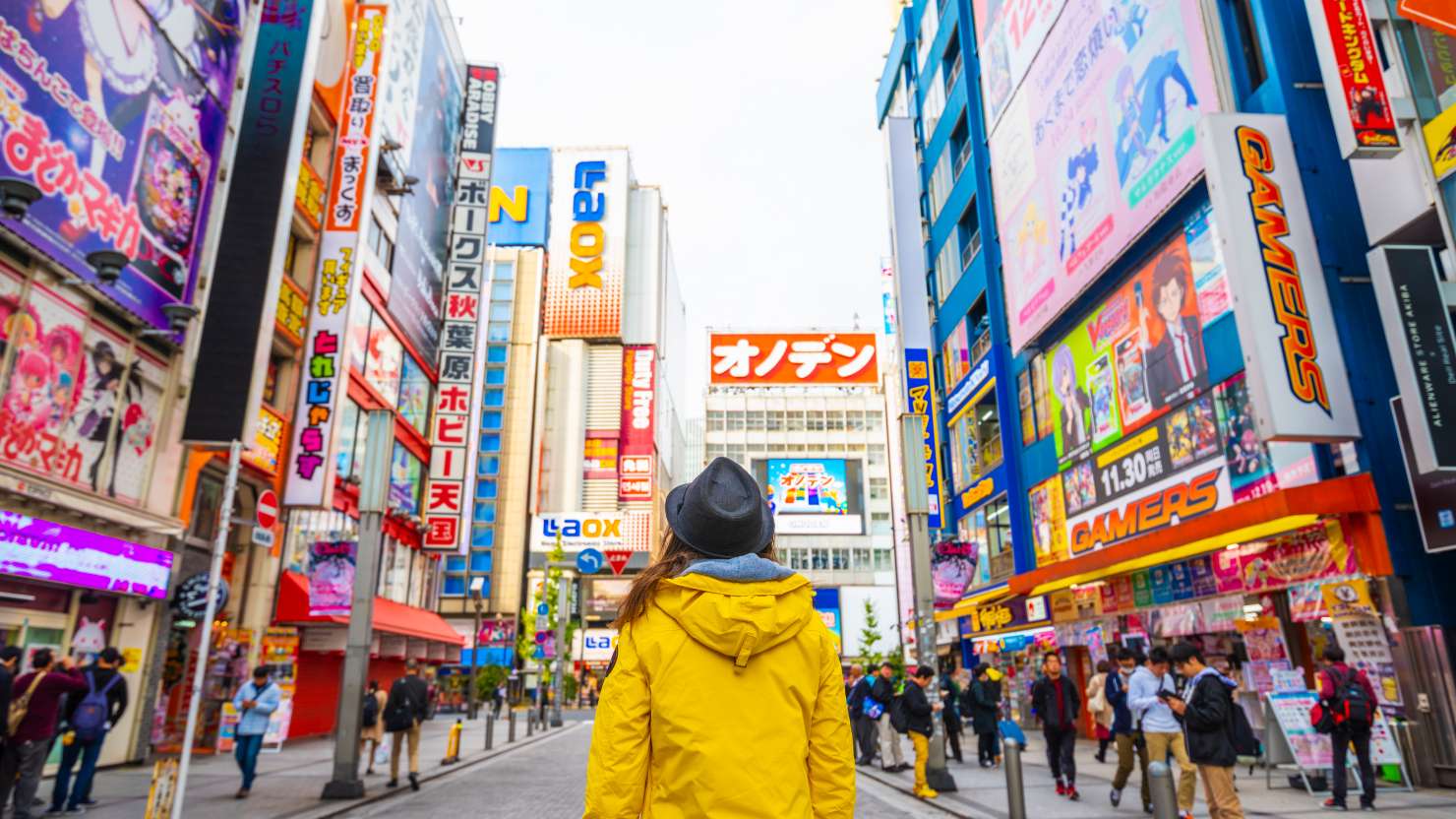 Woman with yellow jacket walking in the electronic town district of Akihabara, the geek ward of Tokyo, Japan