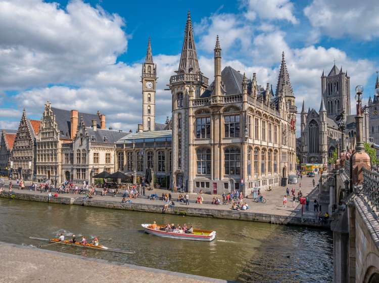 Ghent, Belgium,circa August 2019. People in the Graslei, quay in the promenade next to river Lys in Ghent, Belgium and St Michael's Bridge on a sunny day. Beautiful architecture  of the medieval city.