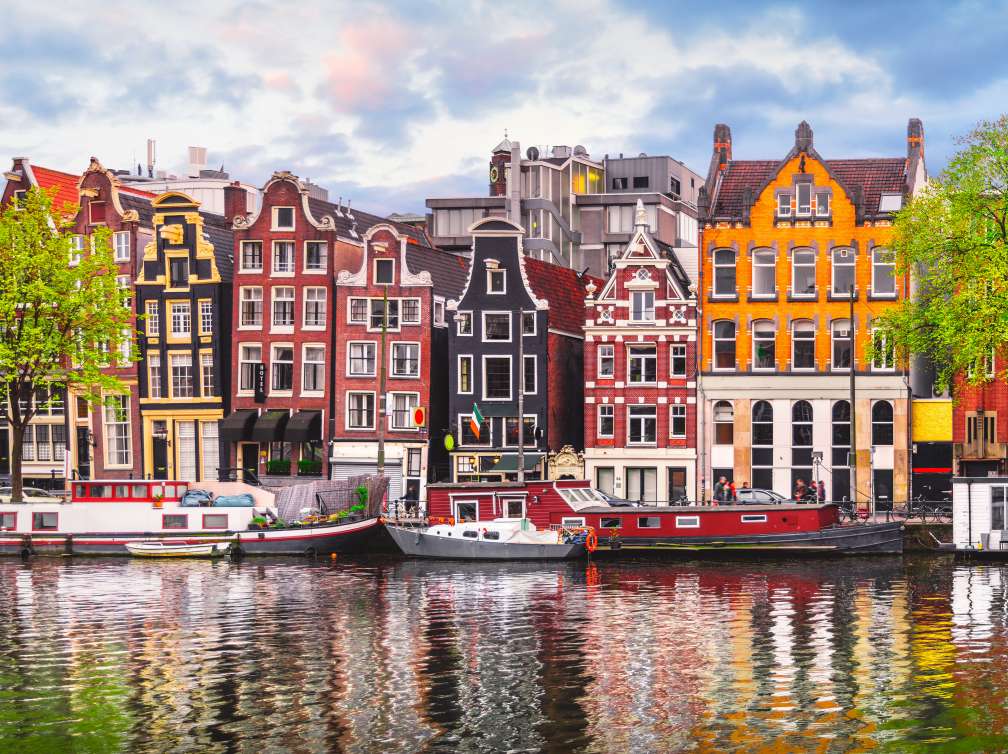  Boats in Amsterdam canal in front of buildings