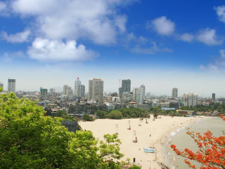A beach infront of tall buildings and a blue sky