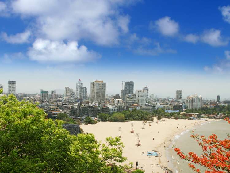 A beach infront of tall buildings and a blue sky