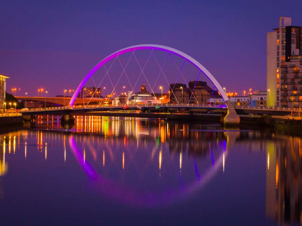 A lit up bridge over water with an evening sky