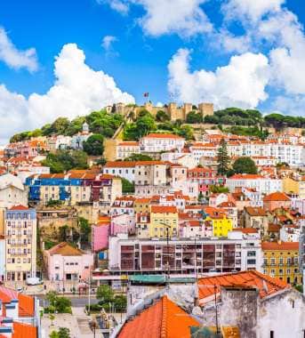 Lots of colourful buildings infront of a castle on a hill