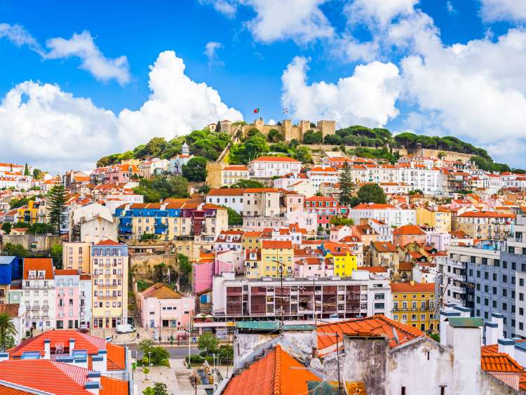 Lots of colourful buildings infront of a castle on a hill