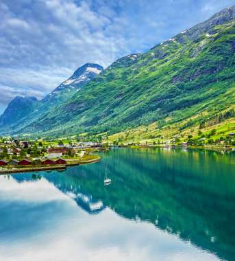  Big green mountains next to water and houses 