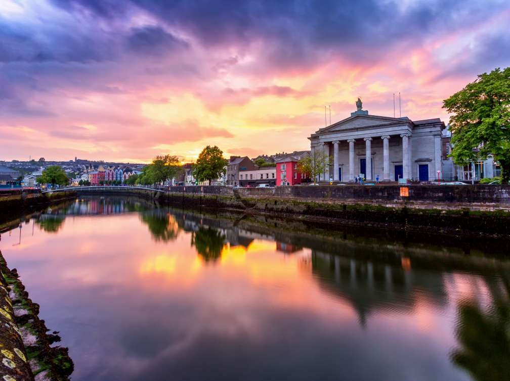  A bridge over water with an orange, pink and purple sky