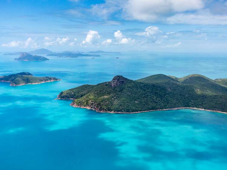 Mountains surrounding sea with bright green plants 