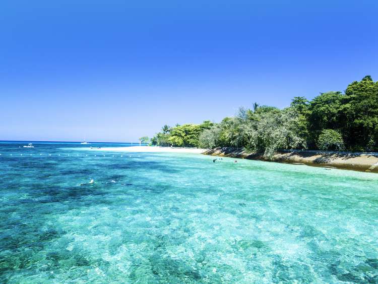 Small beach alongside clear blue sea and clear blue sky
