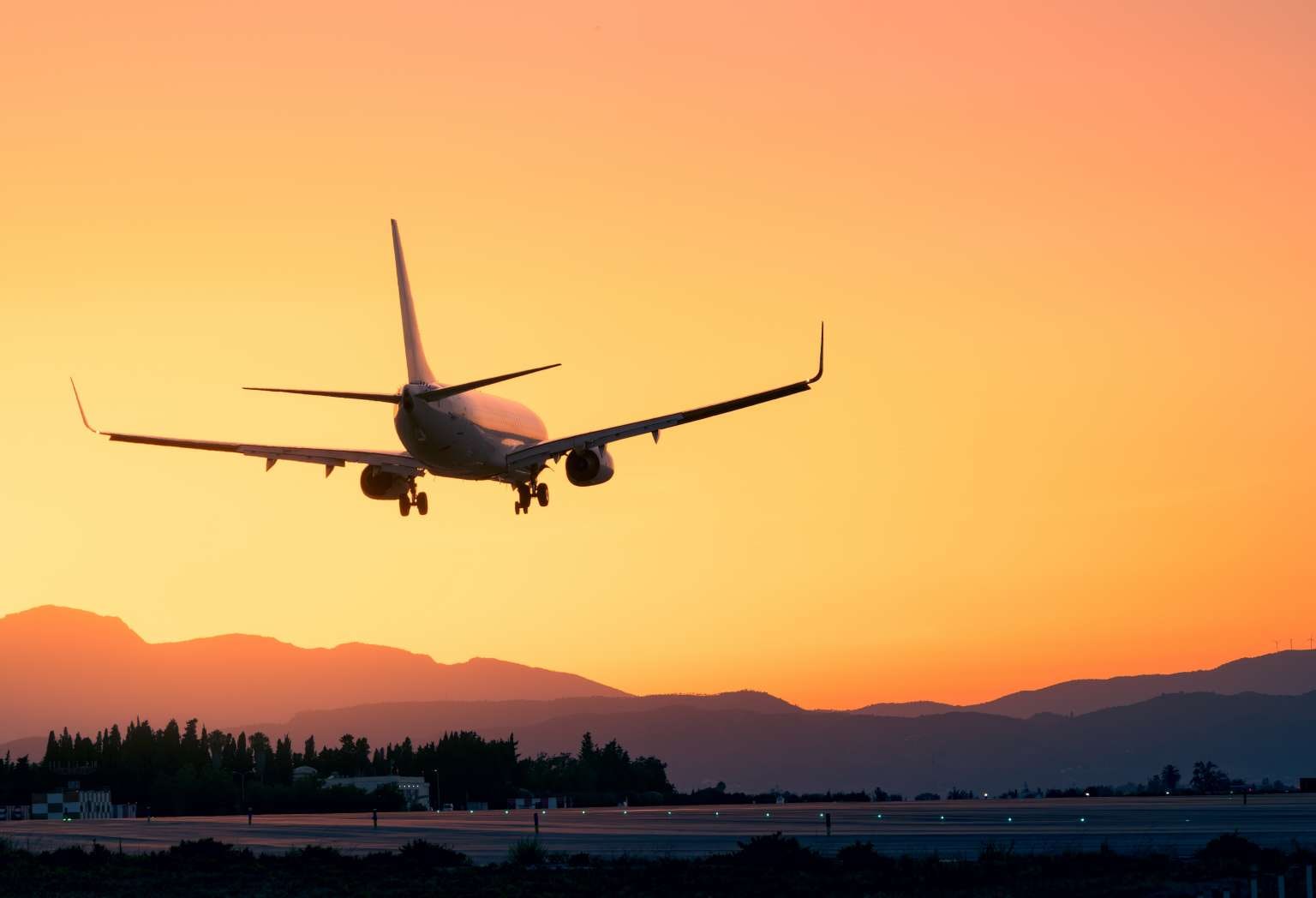 Amidst a breathtaking sunset, an airplane lands gracefully, offering a sense of adventure and escape. With majestic mountains as a backdrop, the scene embodies the beauty and tranquility of a vacation journey.