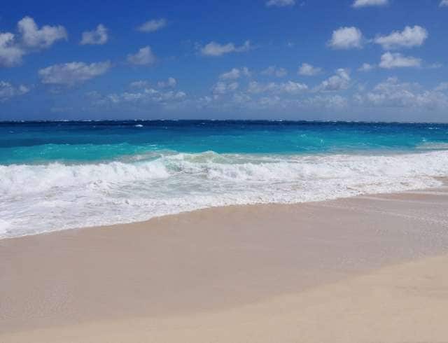 Waves the blue tropical ocean of Barbados crash the  white sand beach