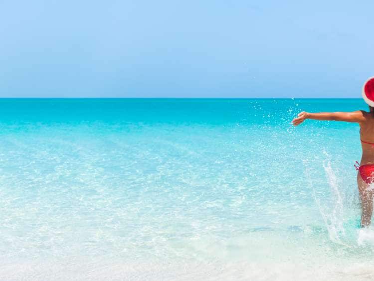 Christmas Caribbean beach tropical Santa Claus woman Happy swimming in blue ocean water panorama banner. Bikini girl with pen arms freedom carefree. Travel vacation holidays under the tropical sun.; Shutterstock ID 1211390023; purchase_order: POC; job: Christmas; client: ; other: 