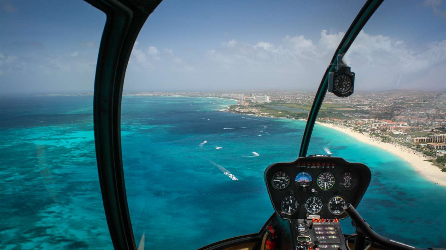 Aerial view of beautiful coastline of tropical Aruba Island from cockpit of small helicopter.