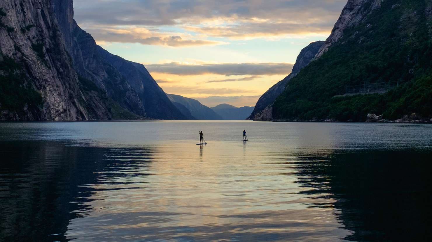 Two people paddle boarding in the Norwegian Fjords