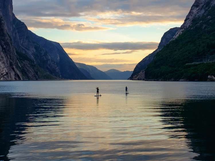 Two people paddle boarding in the Norwegian Fjords