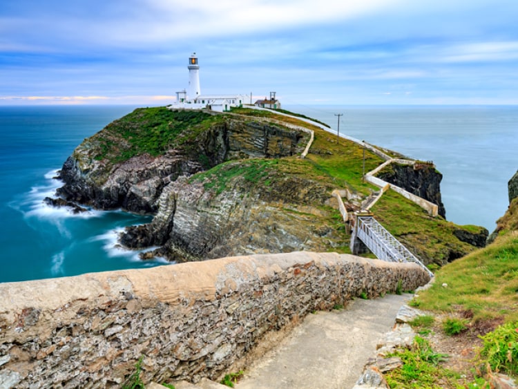 A lighthouse on a cliff surrounded by water