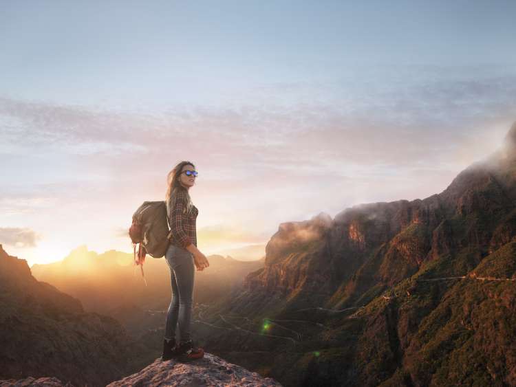 Alone trekking woman in mountains at sunset
