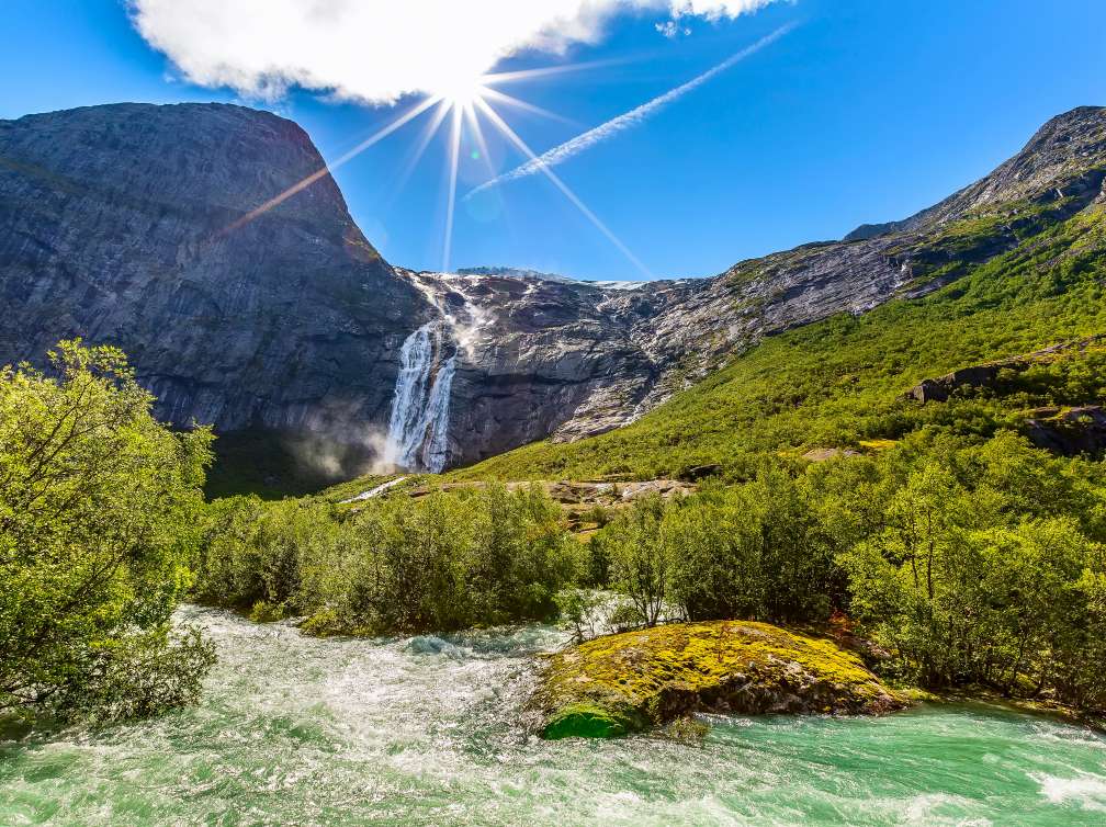 Waterfall, river and green trees on the way to Briksdal or Briksdalsbreen glacier in Olden, Norway