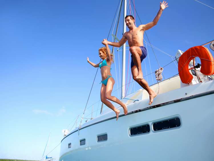 Young couple jumping in water from yacht