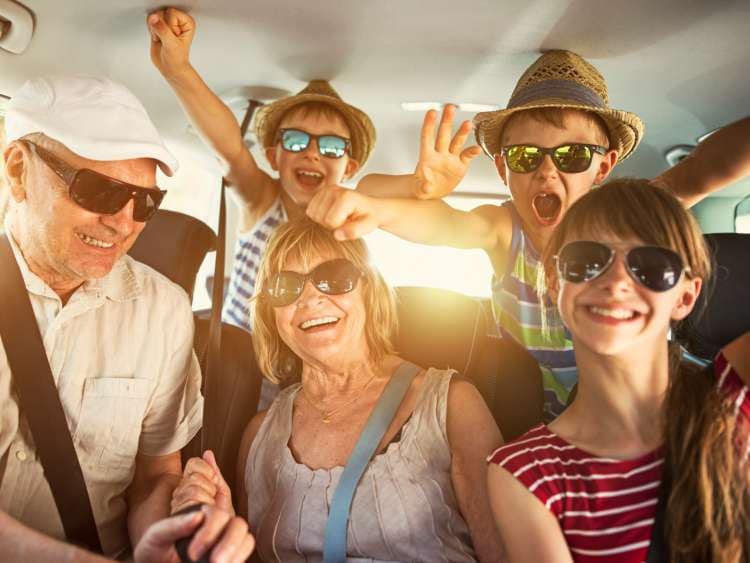 Senior couple aged 70 and their three grandchildren aged 11 and 7 are having fun during road trip. 