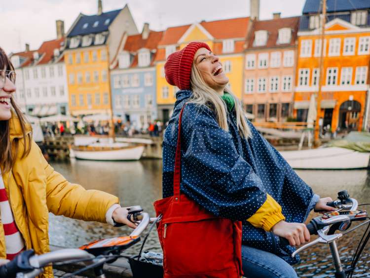 Photo of two young women riding bikes and having fun while discovering the new city together.