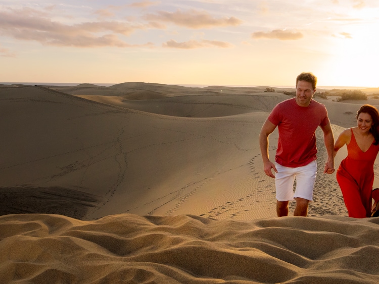 Couple walking through sand dunes