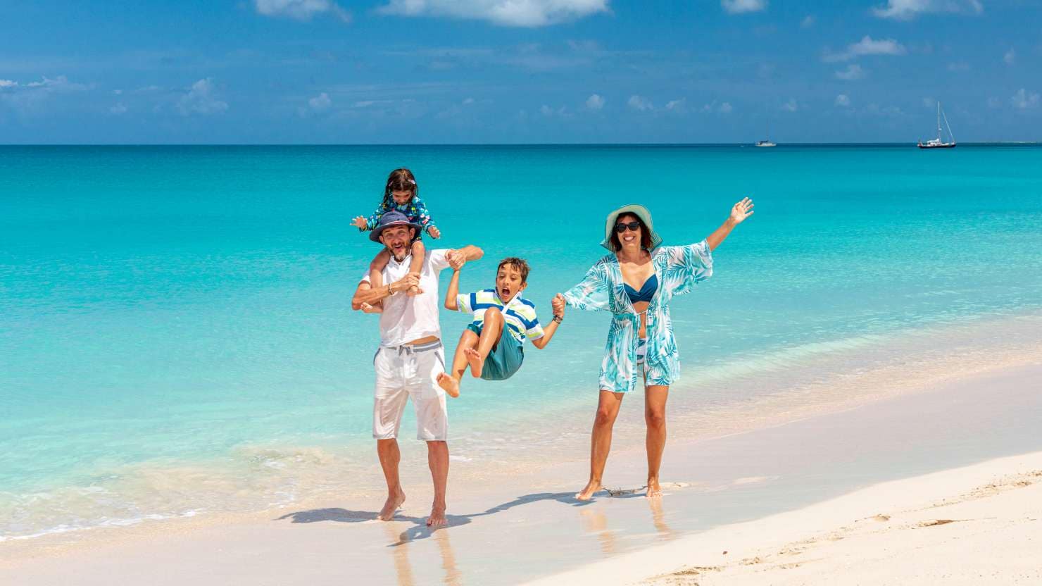 Happy parents carrying the little daughter piggyback and swinging the cute son on a beach, Antigua and Barbuda, Caribbean, West Indies