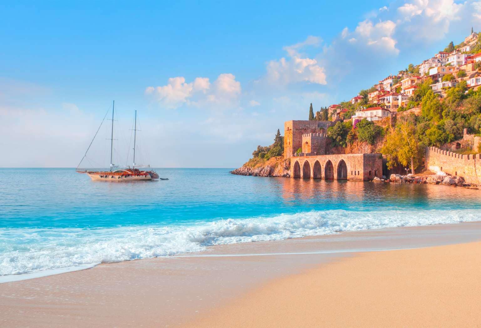 Beautiful sandy beach and soft turqoise Mediterranean sea wave - Landscape of ancient shipyard near of Kizil Kule tower - Alanya peninsula, Turkey; Shutterstock ID 1965918337; project: olly; job: ; client: pocruises; other: 