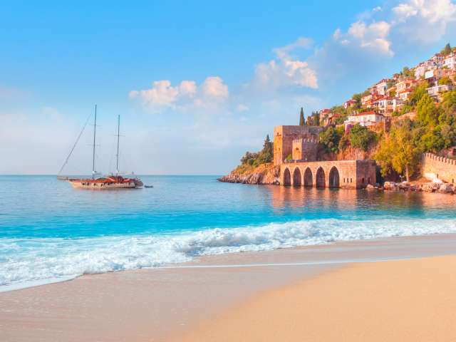Beautiful sandy beach and soft turqoise Mediterranean sea wave - Landscape of ancient shipyard near of Kizil Kule tower - Alanya peninsula, Turkey; Shutterstock ID 1965918337; project: olly; job: ; client: pocruises; other: 