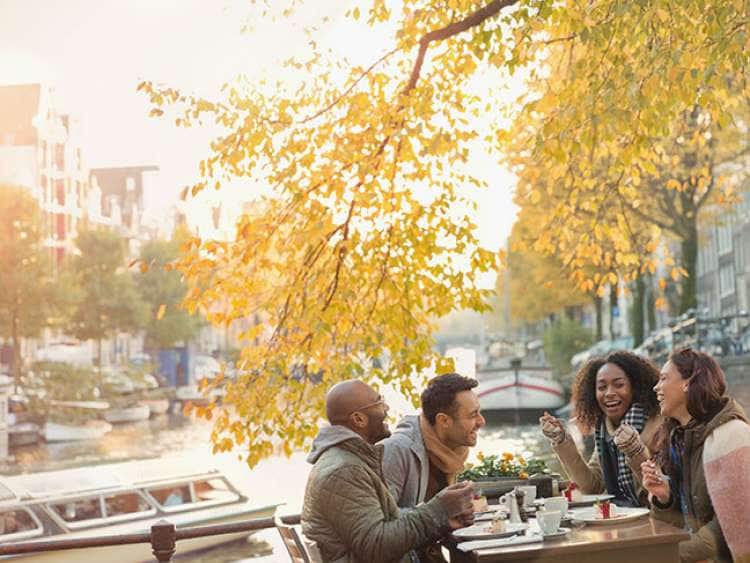 Group of people sat on table by the river enjoying food in Amsterdam, Netherlands