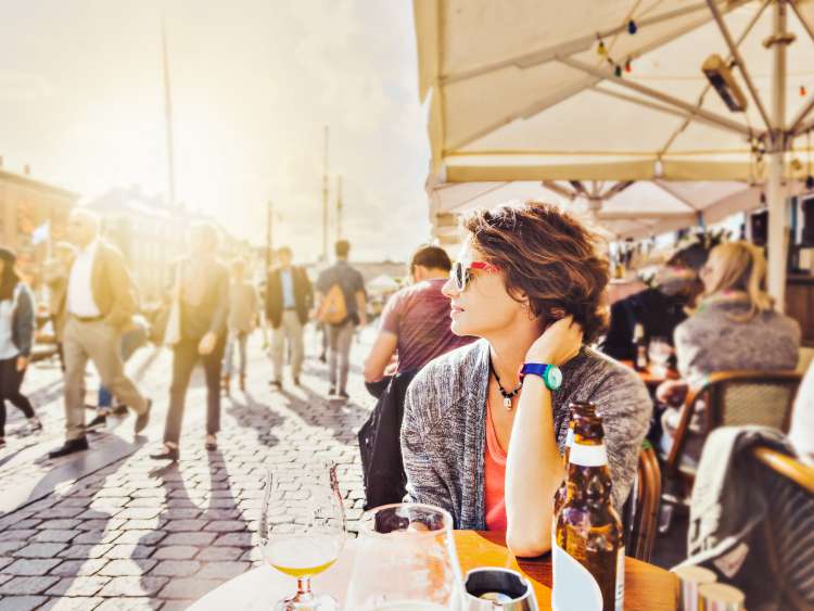 Young woman sitting in a street cafe drinking beer and watching the city life, Europe lifestyle. Denmark, Copenhagen, Nyhavn; Shutterstock ID 755371195; project: olly; job: ; client: pocruises; other: 